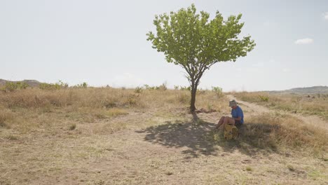 Female-hiker-rests-in-shade-of-lone-tree-hot-day-Cappadoccia-Turkey