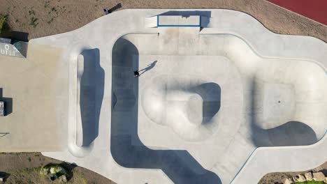 Bird-eye-aerial-view-captures-the-dynamic-movement-of-skateboarder-in-a-slow-motion-spectacle-at-the-skate-park-playground