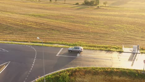 Silver-car-moving-on-the-new-asphalt-road-in-sunset--aerial-drone-shot