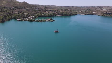 Lone-boat-anchored-in-middle-of-stunning-Green-lake,-Taurus-mountains-Turkey,-aerial-descend