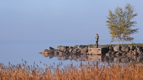 Scene-of-young-man-alone-on-shore-enjoying-autumn-landscape