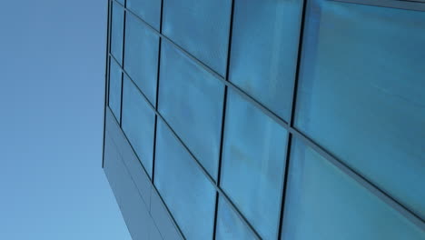 Low-angle-view-of-blue-reflective-skyscraper-facade-against-a-clear-sky
