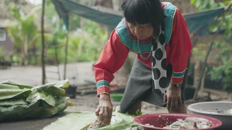 Indigenous-Woman-stuffing-a-fish-with-herbs,-Amazonian-Jungle,Peru