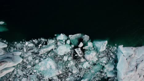 Aerial-top-down,-melted-ice-chunks-in-dark-cold-glacial-lake-Jokulsarlon-Iceland