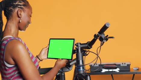 Mujer-Alegre-Siguiendo-Videos-Tutoriales-En-Una-Tableta-De-Maqueta,-Aprendiendo-A-Reparar-Bicicletas