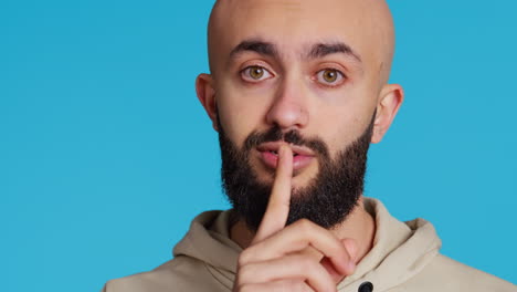 Middle-eastern-person-showing-mute-gesture-with-finger-over-lips