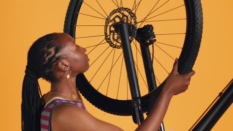 Mujer-Desconectando-La-Rueda-De-La-Bicicleta-Y-Ajustando-El-Manillar,-Fondo-Del-Estudio