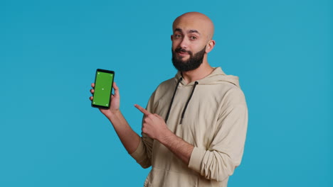 Muslim-guy-holding-smartphone-with-greenscreen-display