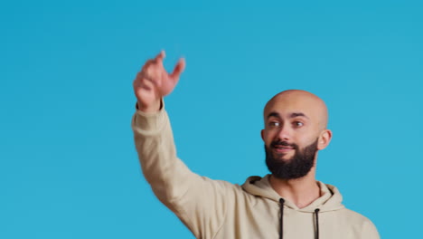 Middle-eastern-guy-welcoming-people-in-studio-with-a-wave