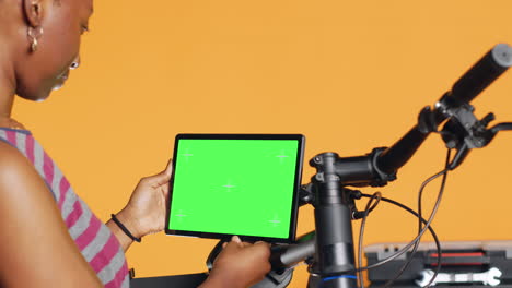 Mechanic-doing-bike-servicing,-looking-on-green-screen-tablet