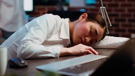 Tired-employee-sleeping-on-workspace-desk,-awaken-by-coworker,-laughing