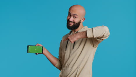 Middle-eastern-man-presenting-greenscreen-on-smartphone