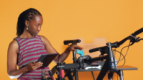 Mujer-Siguiendo-Clips-De-Tutoriales-De-Internet-En-Una-Tableta,-Aprendiendo-A-Arreglar-Una-Bicicleta-Dañada