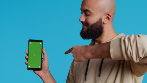 Muslim-guy-holding-smartphone-with-greenscreen-display