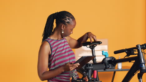 Mujer-Siguiendo-Una-Guía-En-Línea-En-La-Pantalla-De-Una-Tableta-Para-Aprender-Cómo-Reparar-Una-Bicicleta-Que-No-Funciona-Correctamente.