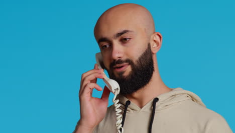 Muslimischer-Erwachsener,-Der-Im-Studio-Einen-Anruf-über-Ein-Festnetztelefon-Entgegennimmt
