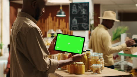 African-american-buyer-shows-tablet-with-greenscreen-template-in-grocery-store
