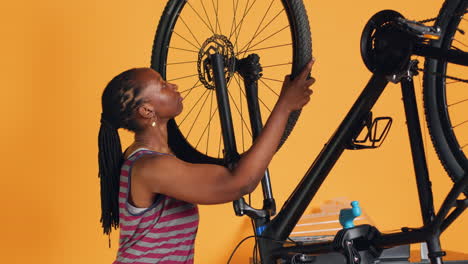 Engineer-doing-bike-servicing-in-studio-background,-replacing-defective-wheel