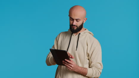 Chico-árabe-Usando-Tableta-Para-Desplazarse-Por-Sitios-Web-En-Línea