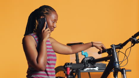 Woman-talking-on-phone-with-mechanic,-asking-for-help-on-repairing-damaged-bike