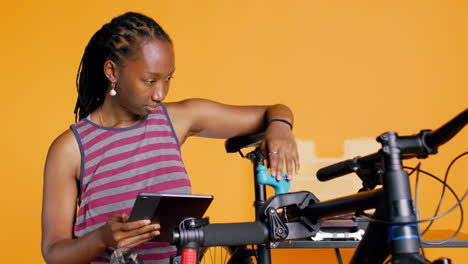 Mujer-Siguiendo-Una-Guía-En-Línea-En-La-Pantalla-De-Una-Tableta-Para-Aprender-Cómo-Reparar-Una-Bicicleta-Que-No-Funciona-Correctamente.