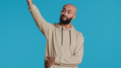 Arab-man-waving-at-a-person-while-posing-in-studio