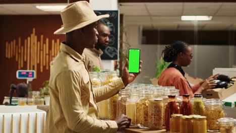 African-american-seller-holding-smartphone-app-with-greenscreen