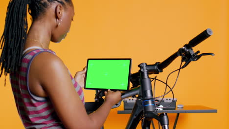 Mujer-Alegre-Siguiendo-Videos-Tutoriales-En-Una-Tableta-De-Maqueta,-Aprendiendo-A-Reparar-Bicicletas