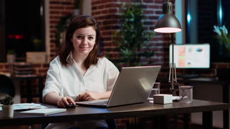 Portrait-of-smiling-accountant-sitting-at-office-desk-in-front-of-laptop