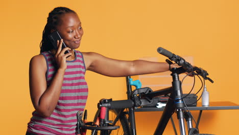 Cheerful-engineer-at-work-taking-break-from-repairing-bike,-talking-on-phone