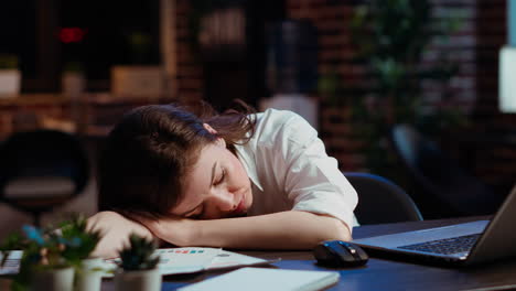 Sleepy-employee-asleep-on-computer-desk-late-at-night-in-brick-wall-office