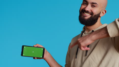 Middle-eastern-man-presenting-greenscreen-on-smartphone