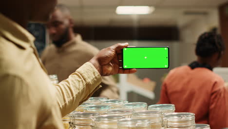 African-american-seller-shows-greenscreen-display-on-mobile-phone