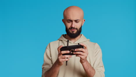 Fröhlicher-Muslimischer-Mann,-Der-Im-Studio-Mobile-Videospiele-Spielt