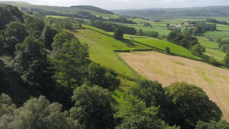 Drone-footage-moving-slowly-and-sideways-over-a-shallow-valley-near-the-rural-village-of-Settle,-North-Yorkshire,-UK