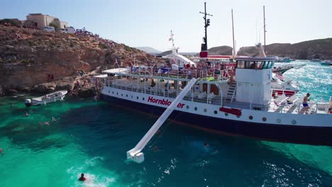 People-Using-Long-Water-Slide-on-Tourist-Day-Trip-Ferry-Boat,-Blue-Lagoon,-Malta