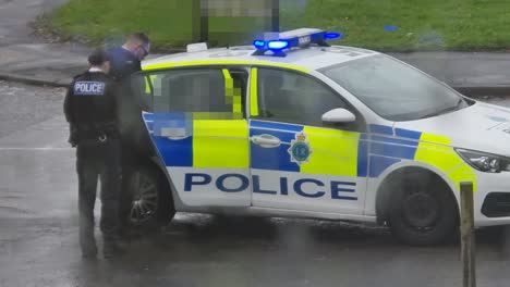 Festgenommener-Mann,-Der-In-Einem-Polizeifahrzeug-Mit-Sichtschutzmosaik-Sitzt,-Um-Die-Identitätsbeobachtung-Vor-Regnerischem-Fenster-Zu-Schützen