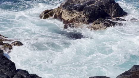 Cinematic-close-up-shot-of-ocean-swell-filling-an-ancient-lava-rock-tide-pool-near-Queen's-Bath-on-the-northern-coast-of-Kaua'i-in-Hawai'i