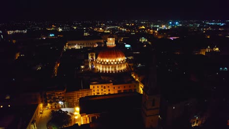 Aerial-Skyline-of-Valletta-at-Night,-Orbiting-Around-Dome-of-Basilica-of-Our-Lady-of-Mount-Carmel,-Malta