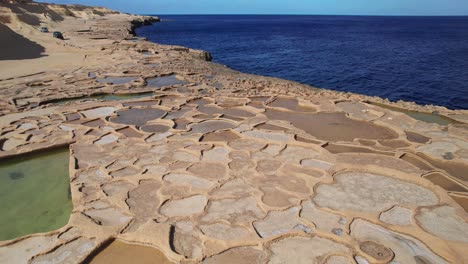 Niedrige-Umlaufbahn-Von-Salzpfannen,-Felsformationen-Und-Blauem-Ozean-Auf-Der-Insel-Gozo,-Malta