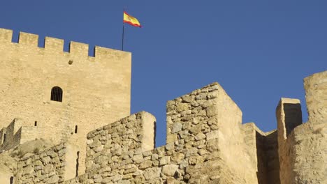 Static-shot-from-below-of-the-Castle-of-Sax-in-Alicante-Valencia-with-the-Spanish-flag-waving-from-the-mast-on-the-defensive-tower