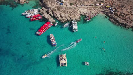 Aerial-of-Tourist-Boats-and-Ferry-Arriving-and-Leaving-Blue-Lagoon,-Comino-Island,-Malta