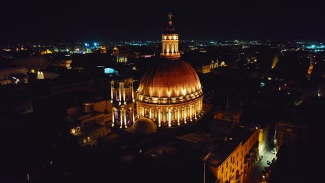 Close-to-Wide-Aerial-Night-Shot-of-Dome-of-Basilica-of-Our-Lady-of-Mount-Carmel,-Valletta,-Malta