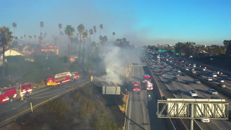 Firefighters-and-firetrucks-working-at-a-busy-road-in-Los-Angeles,-USA---Aerial-view