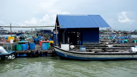An-intricate-depiction-of-the-Malaysian-Fishing-Village-from-a-water-perspective,-reveals-sizable-plastic-containers-and-shelters-situated-on-the-floating-platform