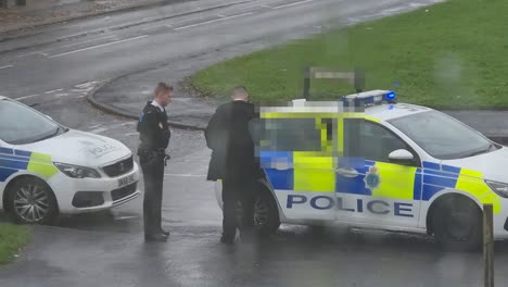 Arrested-male-sitting-in-police-vehicle-with-privacy-mosaic-for-confidentiality,-observation-from-rainy-window