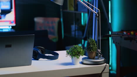 Laptop,-mini-house-plants-and-headphones-on-table-in-empty-room