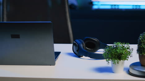 Laptop,-headphones-and-mini-house-plants-on-table-in-apartment-room