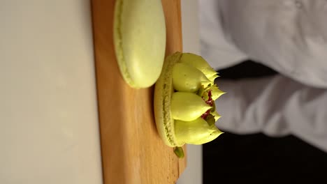 The-French-pastry-chef-adds-pistachios-to-macarons-,-slow-motion-video,-vertical-video