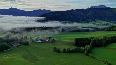 Aerial-drone-shot-over-village-cottages-with-mountain-range-in-the-background-during-morning-time